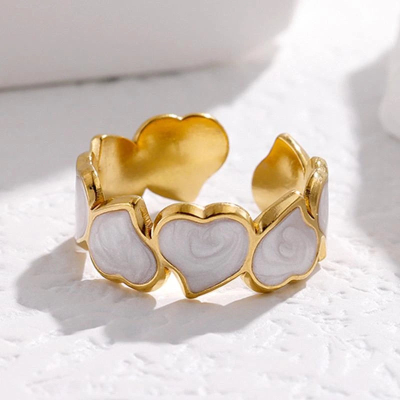 Gold and white heart-shaped ring on a light background