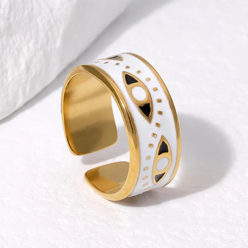 Gold and white cuff ring with black accents on a light background