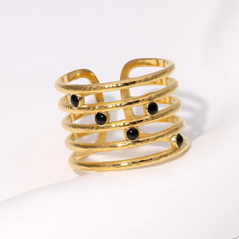 Gold spiral ring with black beads on a white background