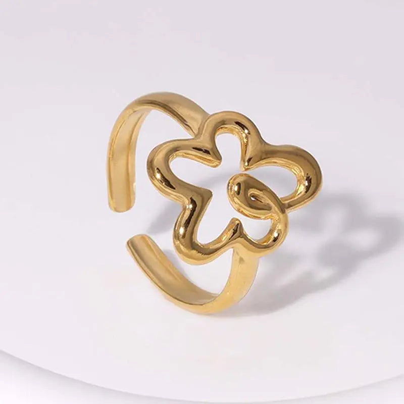 Gold open ring with clover design on a white background